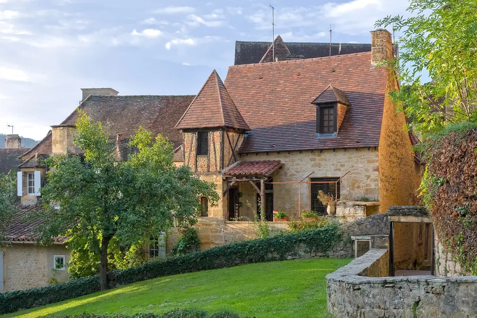 Maisons en pierre blonde de la rue Montaigne à Sarlat-la-Canéda, toits de tuiles brunes et tourelle, vues depuis le jardin des Enfeus.